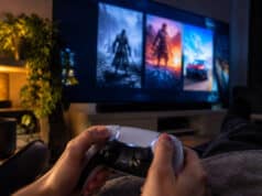 Jeux PS Plus de novembre 2026 : les premières fuites du catalogue Une personne tenant une manette PlayStation 5 face à un grand écran affichant des images de jeux vidéo.