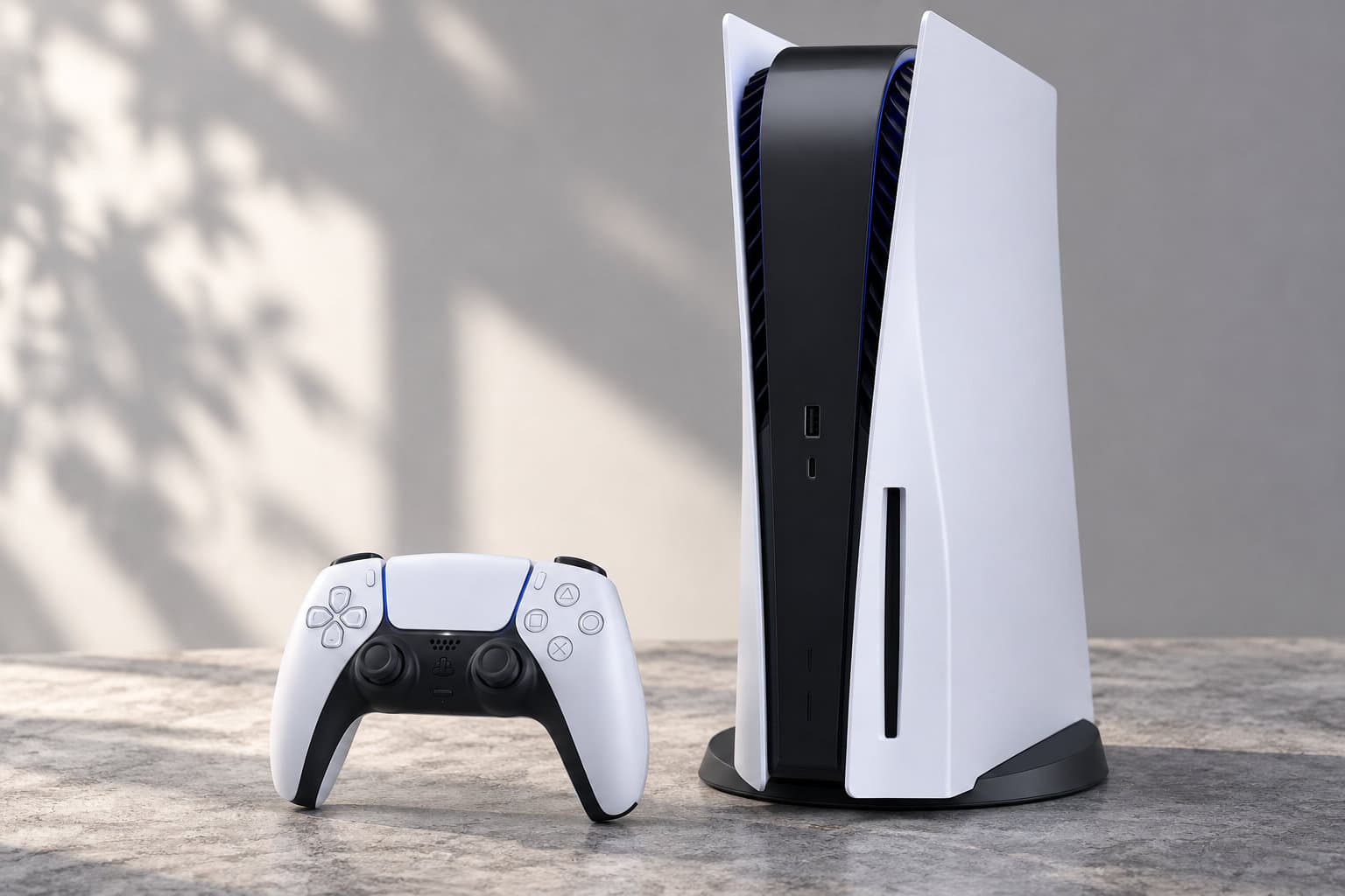 Une console de jeu blanche et noire se tient verticalement à côté d’une manette assortie, sur une surface en pierre.
