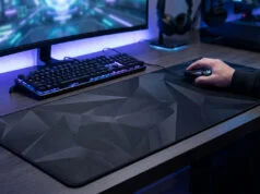Un joueur utilisant une souris sur un large tapis noir à motifs géométriques devant son écran et son clavier rétroéclairé.