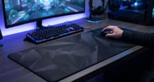 Un joueur utilisant une souris sur un large tapis noir à motifs géométriques devant son écran et son clavier rétroéclairé.
