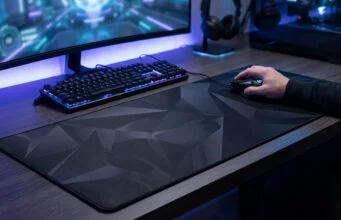 Un joueur utilisant une souris sur un large tapis noir à motifs géométriques devant son écran et son clavier rétroéclairé.